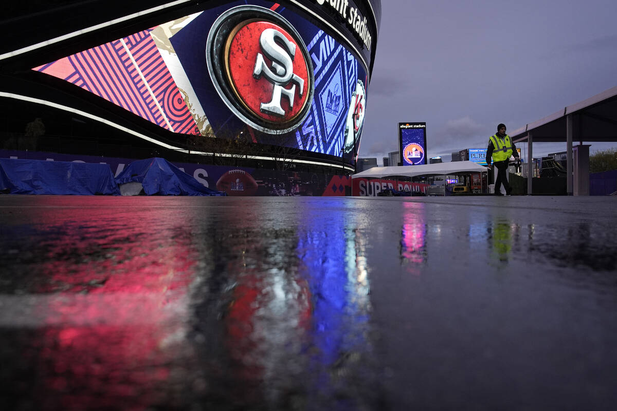 A security guard walks through light rain outside of Allegiant Stadium ahead of the Super Bowl ...