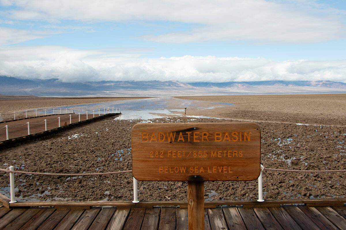 A sign at Badwater Basin describes Death Valley National Park as a hot, dry place. In the backg ...