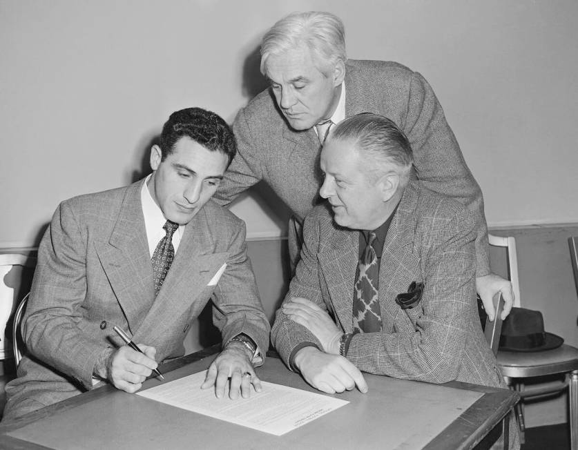 Charley Trippi, left, Georgia football star, signs his $100,000 with Chicago Cardinals at Chica ...