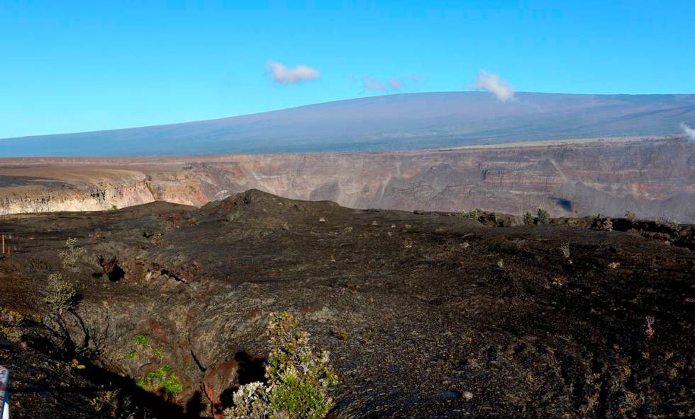 FILE - Hawaii's Mauna Loa volcano, background, towers over the summit crater of Kilauea volcano ...