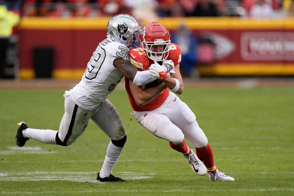 Kansas City Chiefs tight end Travis Kelce, right, is stopped by Las Vegas Raiders cornerback Na ...