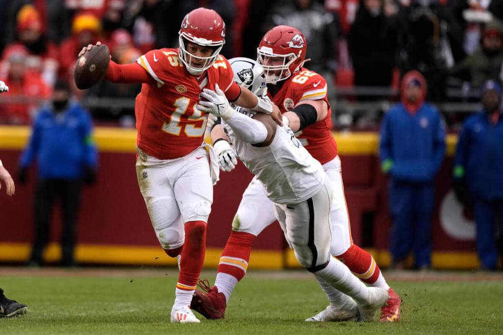 Kansas City Chiefs quarterback Patrick Mahomes (15) slips away from Las Vegas Raiders defensive ...