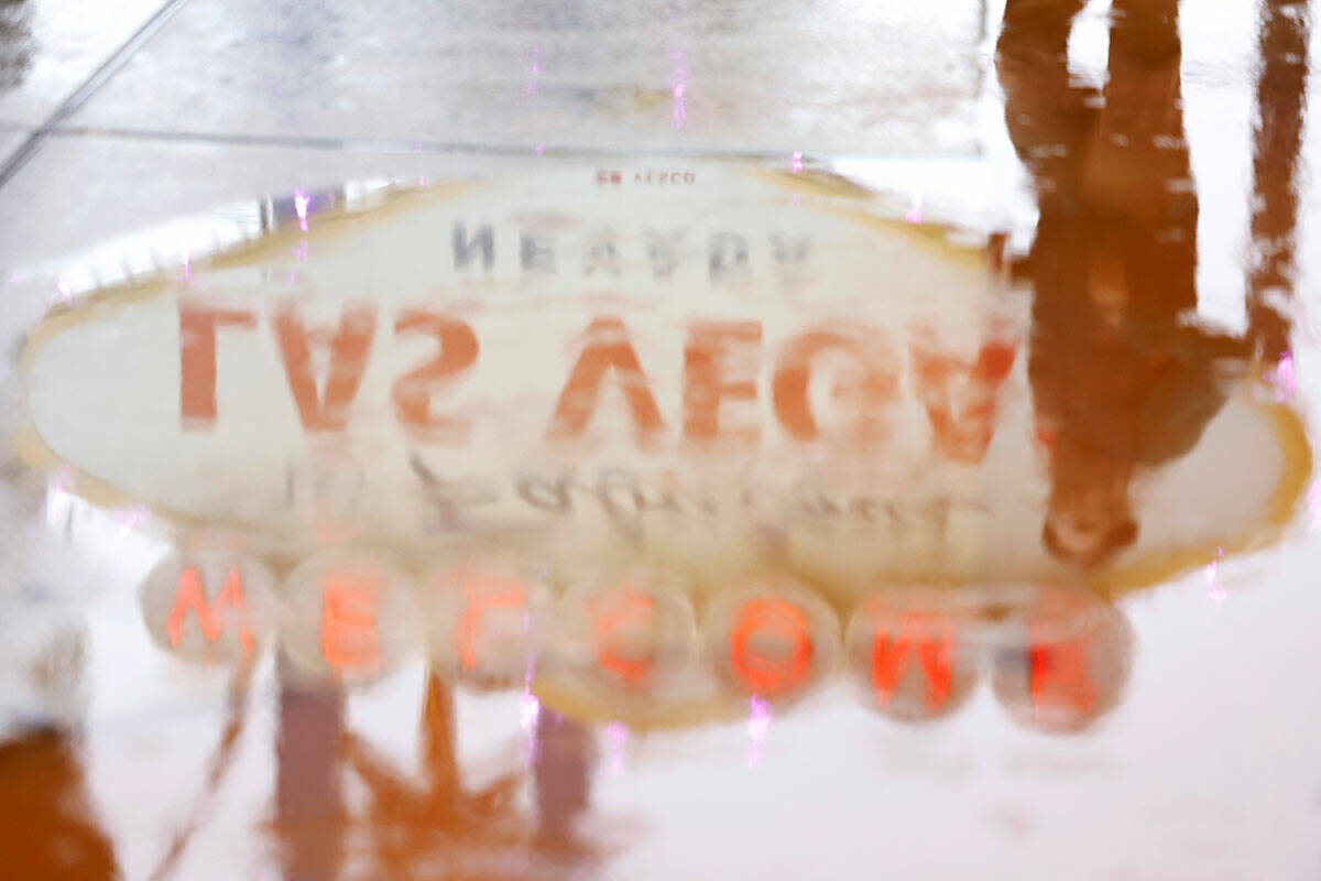 A pedestrian and the “Welcome to Fabulous Las Vegas Nevada” sign are reflected in a puddle ...