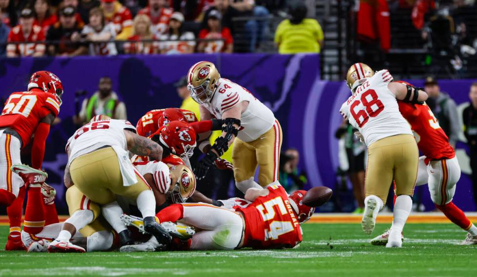 San Francisco 49ers running back Christian McCaffrey, obscured, fumbles the ball during the fir ...