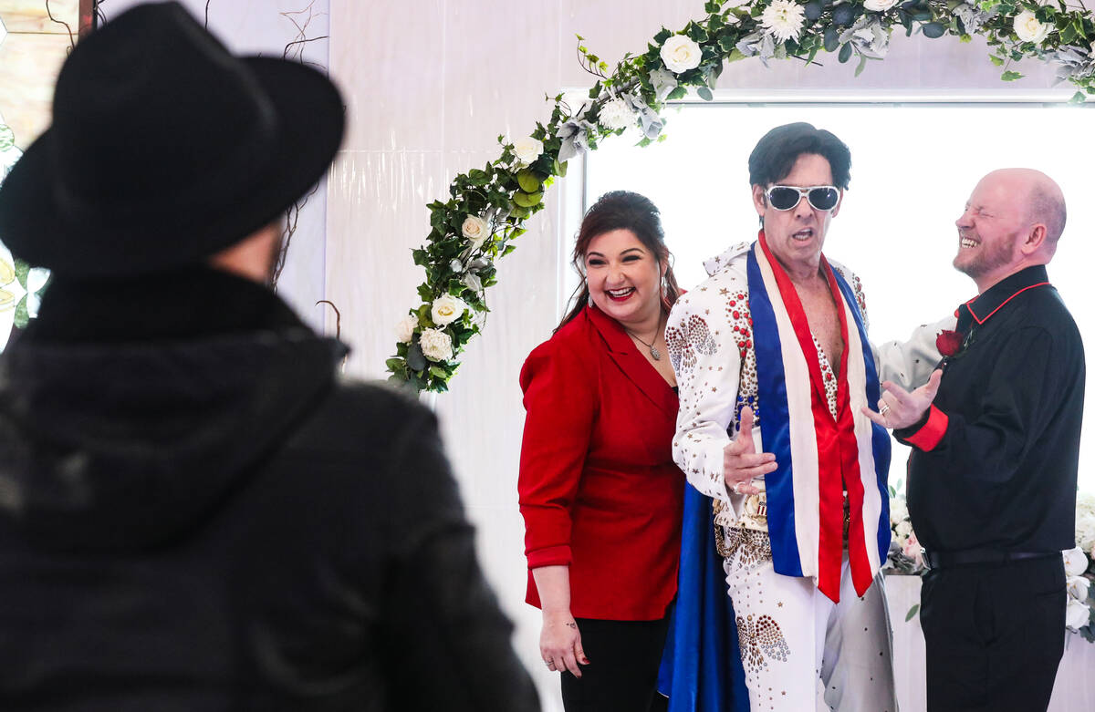 Newlyweds Amanda McIntire, left, poses for a photo with Elvis impersonator Ron Decar, center, a ...