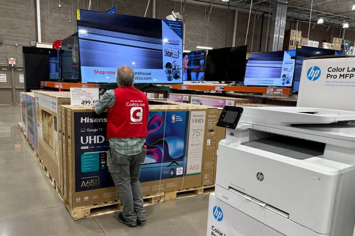 An associate checks over a big-screen television on display in a Costco warehouse Tuesday, Feb. ...