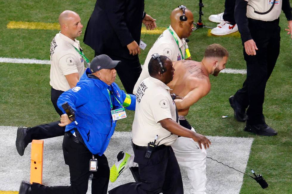 A shirtless Alex Gonzalez is escorted away by security after running on the field during Super ...