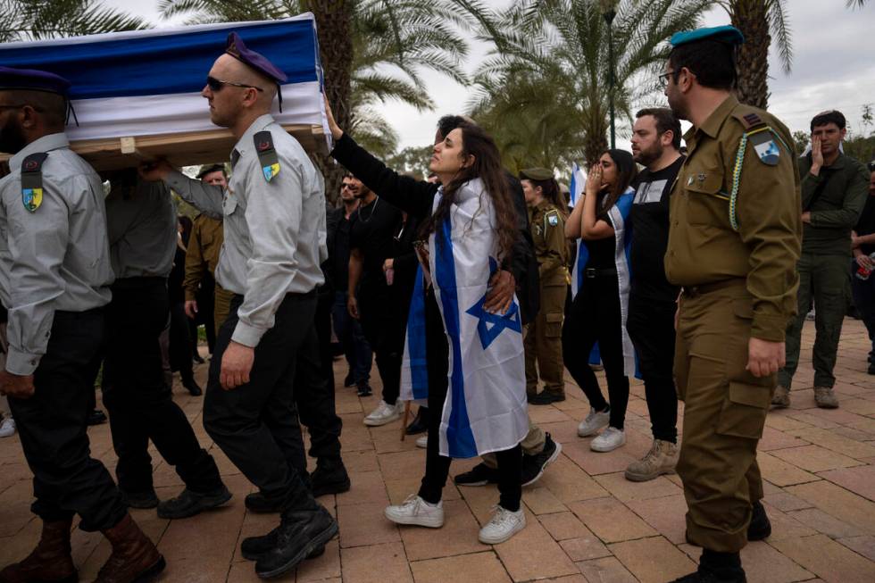 The wife of Israeli reservist Yair Cohen touches his flag-draped casket during his funeral at K ...