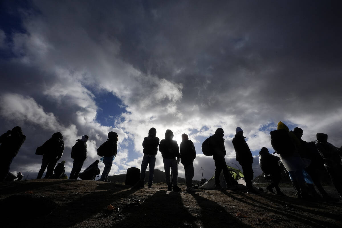 Asylum-seeking migrants wait to be processed in a makeshift, mountainous campsite after crossin ...
