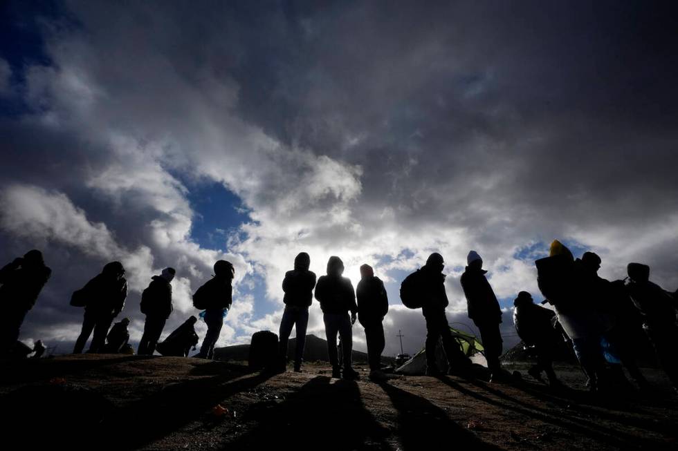 Asylum-seeking migrants wait to be processed in a makeshift, mountainous campsite after crossin ...
