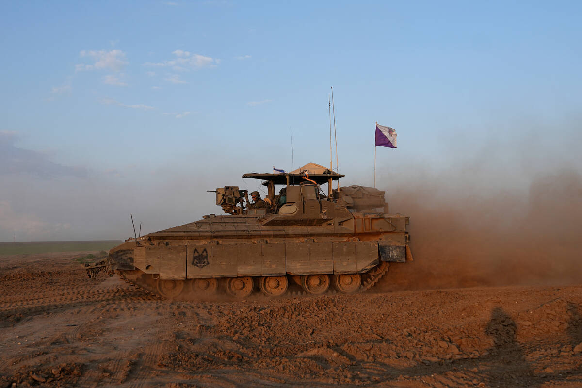 An Israeli soldier stands in the turret of his armored vehicle in southern Israel near the Gaza ...