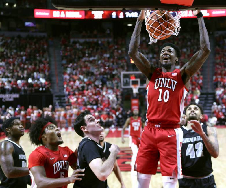 UNLV Rebels forward Kalib Boone (10) dunks the ball as UNR forward Nick Davidson (11) looks on ...