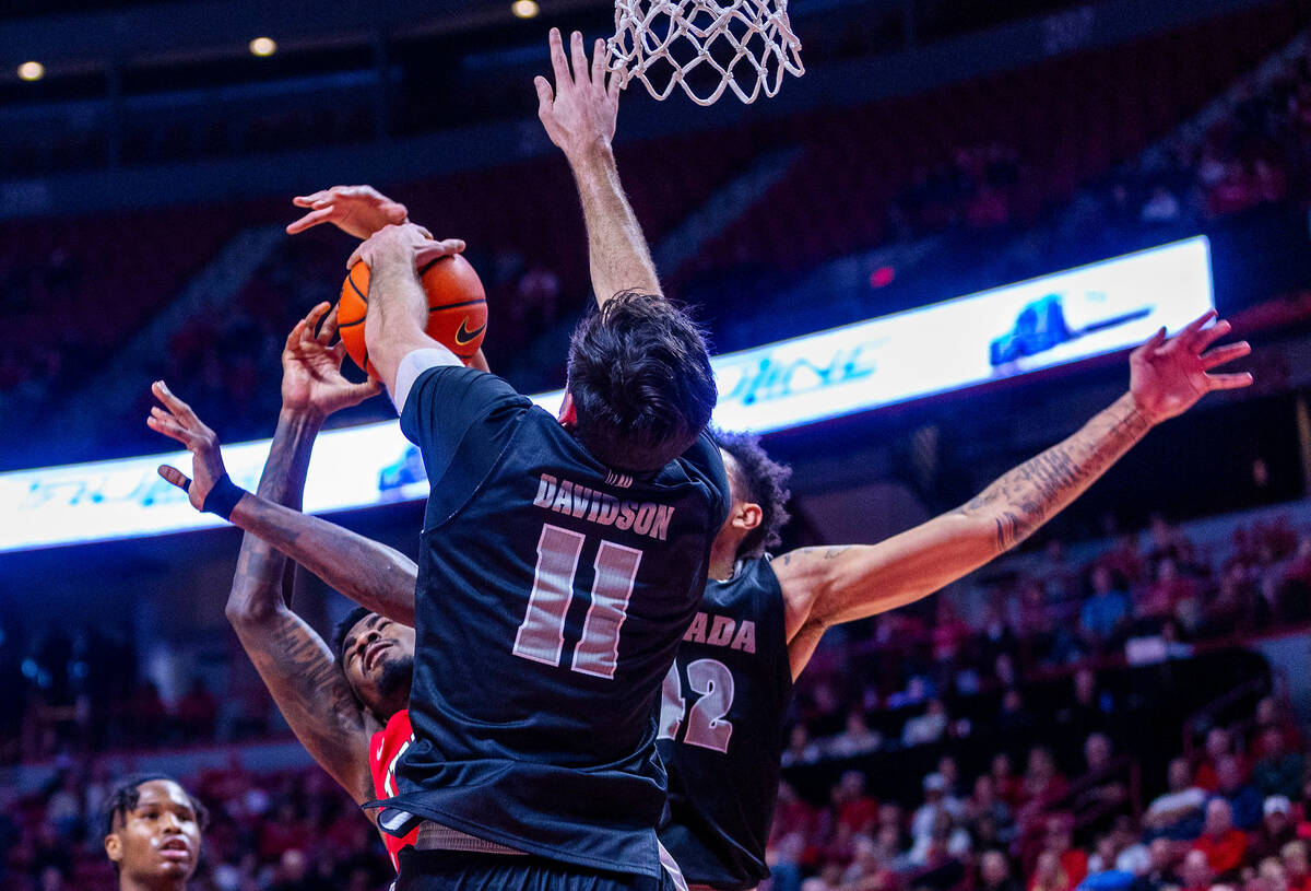 UNLV Rebels forward Kalib Boone (10) has a shot rejected by UNR forward Nick Davidson (11) duri ...