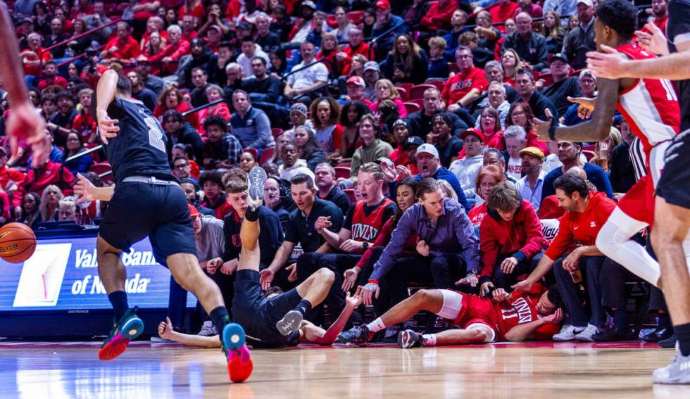 UNR guard Daniel Foster (20) and UNLV Rebels guard Dedan Thomas Jr. (11) end up in the crowd af ...