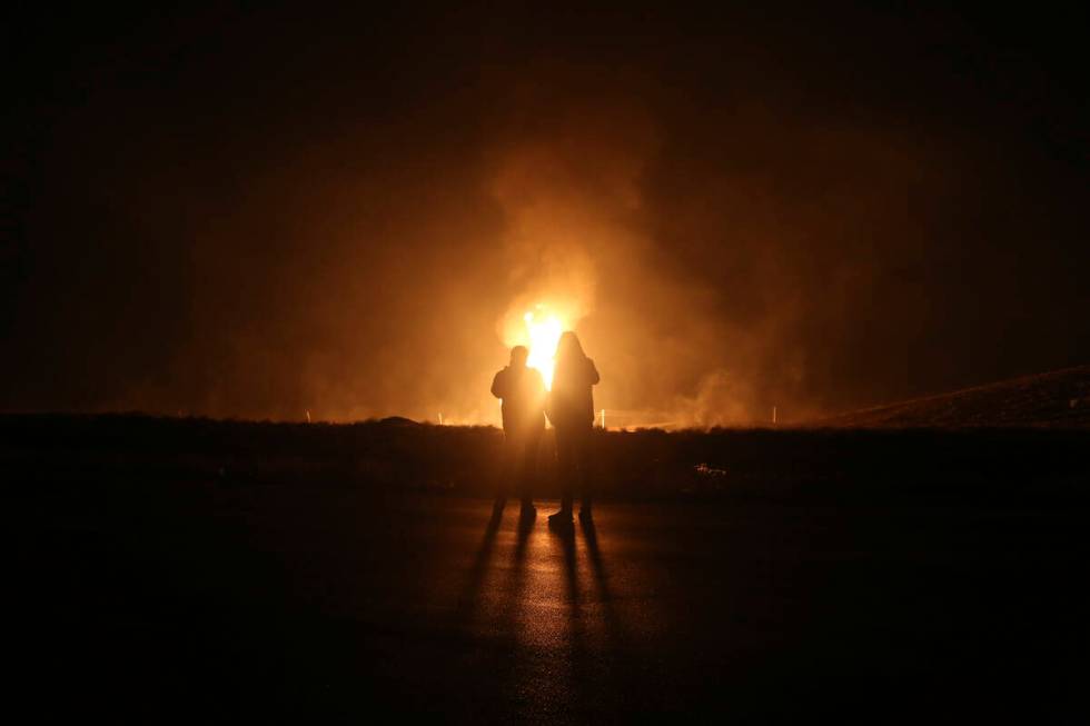 Two men look at flames after a natural gas pipeline explodes outside the city of Boroujen in th ...