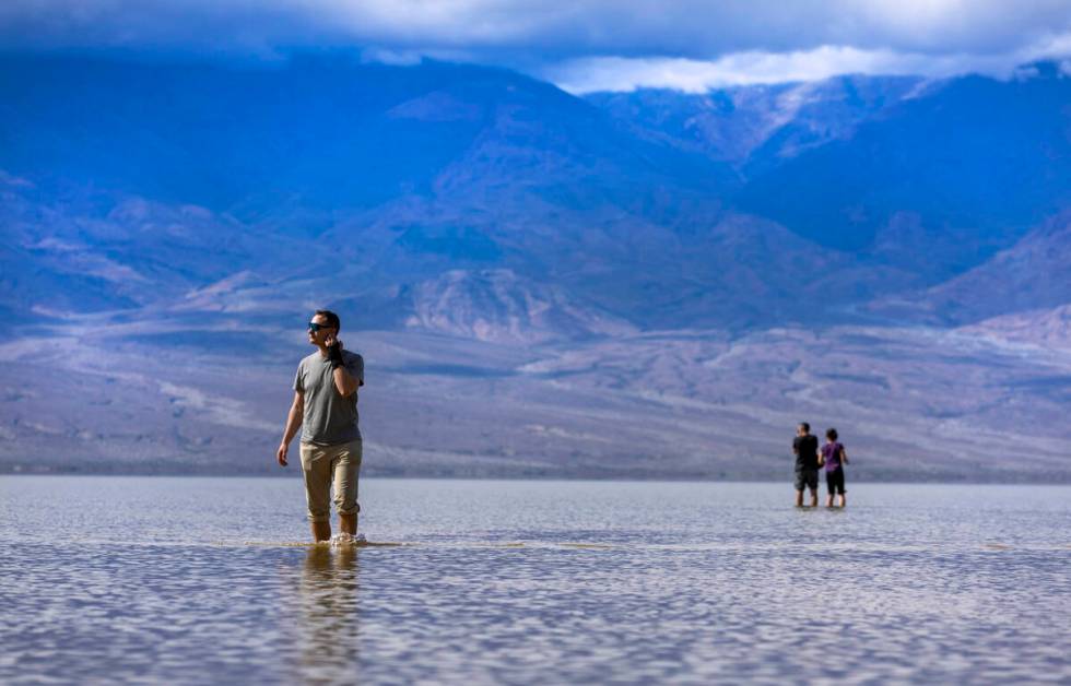 Visitors wander out onto the temporary Lake Manly at Badwater Basin in Death Valley National Pa ...