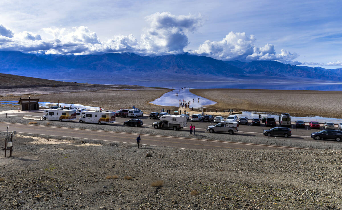 People wander in and out of the water on the temporary Lake Manly at Badwater Basin in Death Va ...