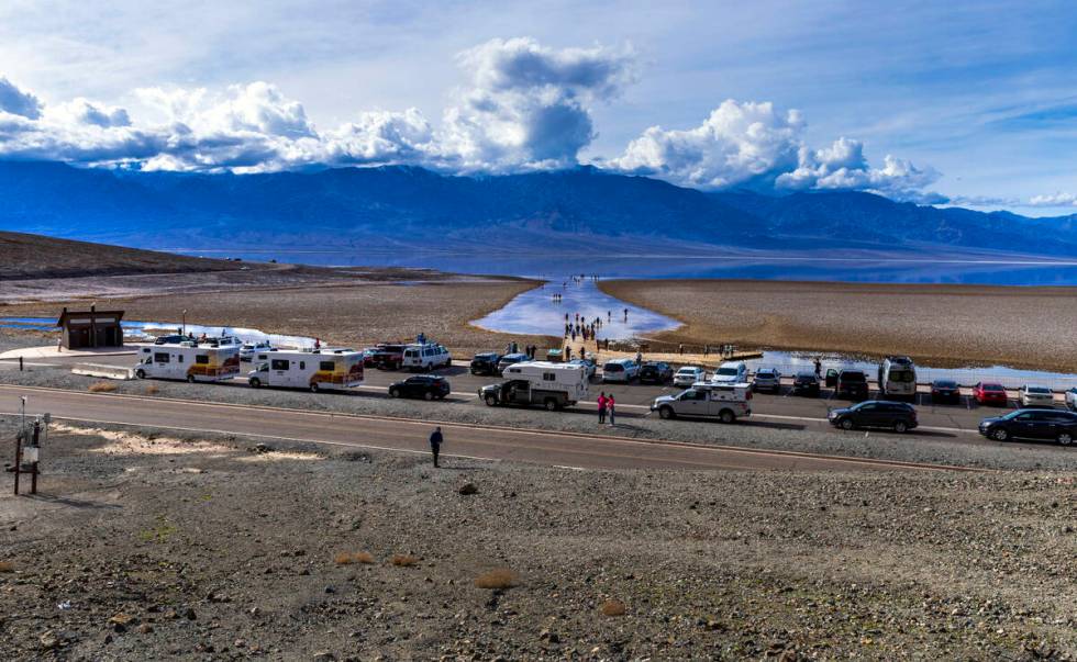 People wander in and out of the water on the temporary Lake Manly at Badwater Basin in Death Va ...