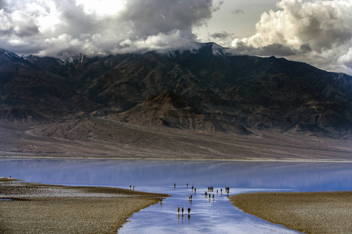 People wander in and out of the water on the temporary Lake Manly at Badwater Basin in Death Va ...