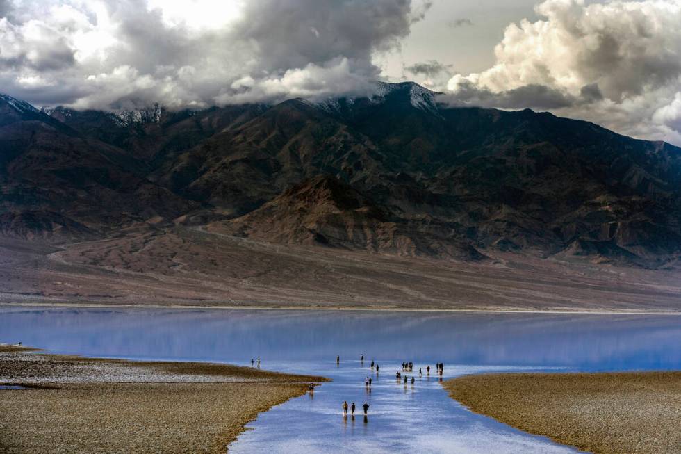 People wander in and out of the water on the temporary Lake Manly at Badwater Basin in Death Va ...