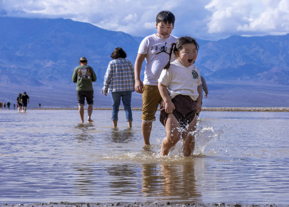 People wander in and out of the water on the temporary Lake Manly at Badwater Basin in Death Va ...