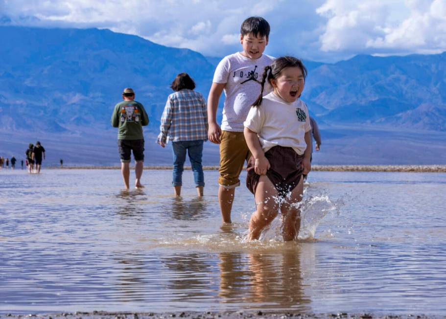 People wander in and out of the water on the temporary Lake Manly at Badwater Basin in Death Va ...