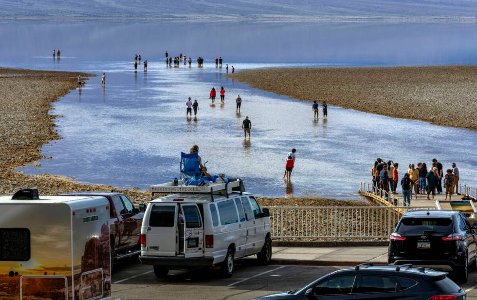 People wander in and out of the water on the temporary Lake Manly at Badwater Basin in Death Va ...