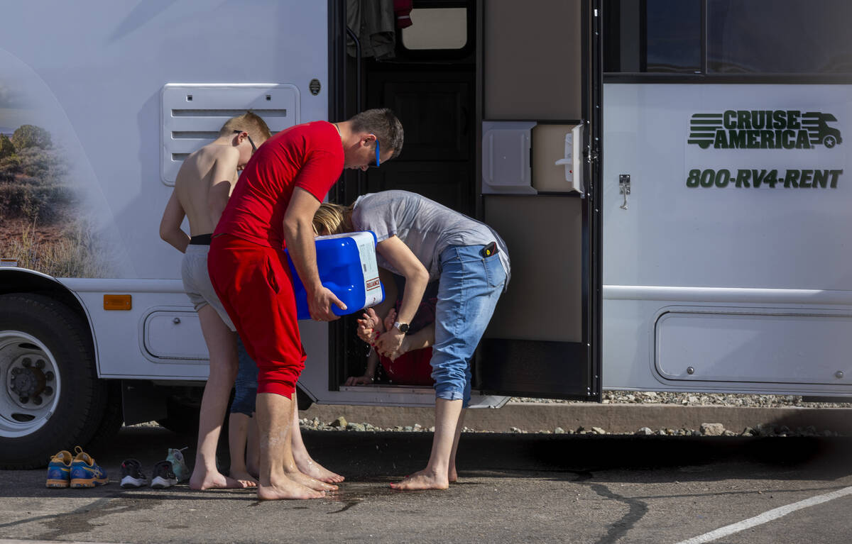 Visitors wash the mud off their feet after walking in the shallow water on the temporary Lake M ...