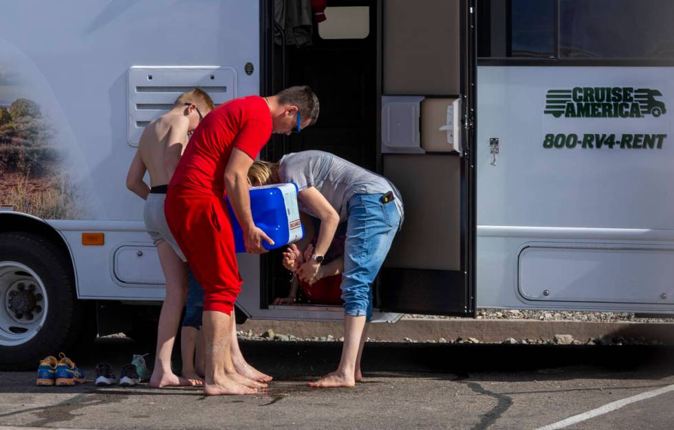 Visitors wash the mud off their feet after walking in the shallow water on the temporary Lake M ...