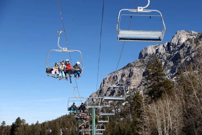 Young skiers and snowboarders ride the chair lift up the mountain at Lee Canyon Ski Arena on Sa ...