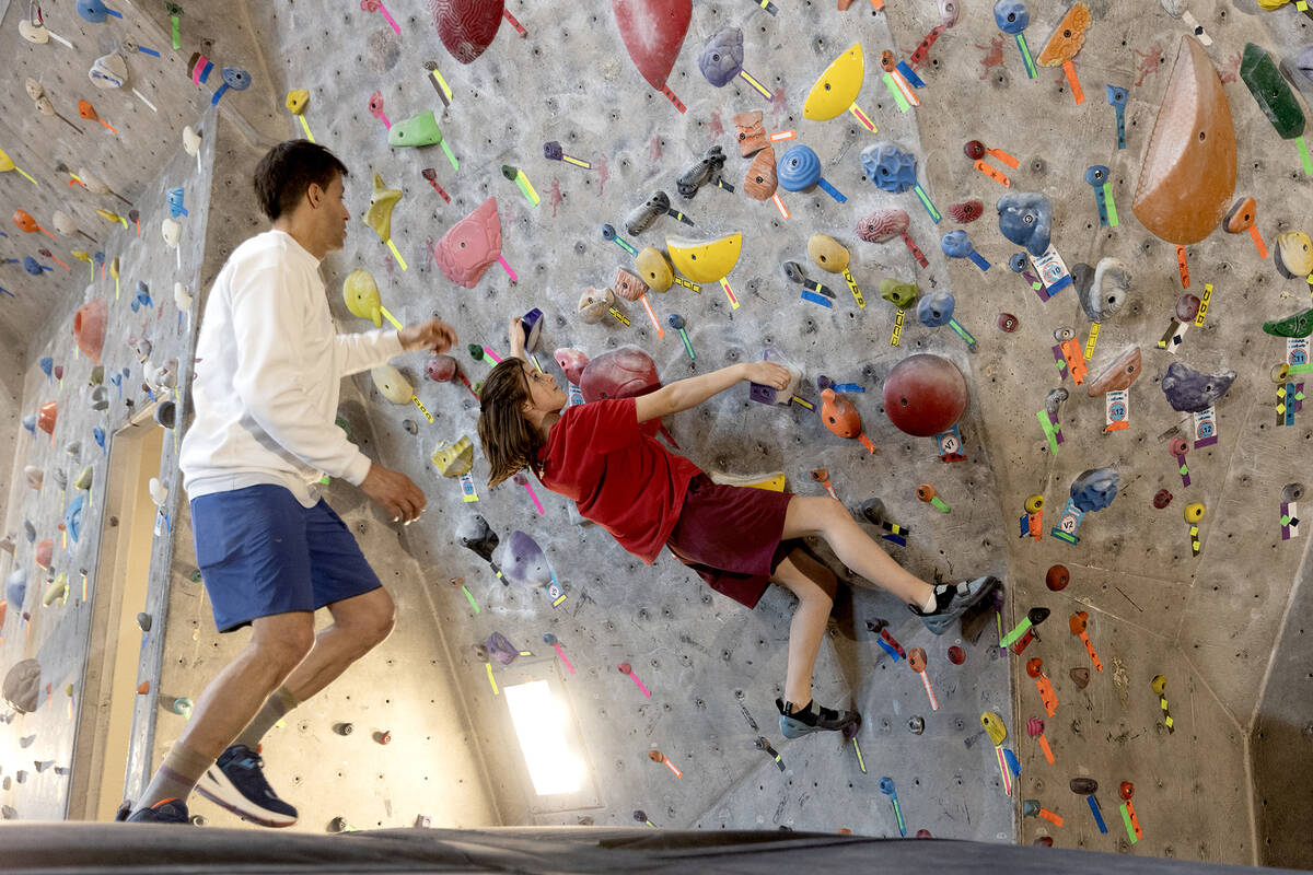 Left, owner and youth climbing team coach Mike Lorenzo helps Audrey Stroud, 13, as she works th ...