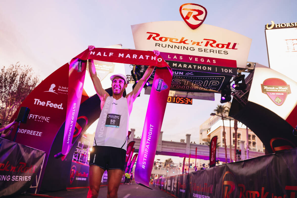 Andy Wacker raises the half marathon finishing line ribbon after coming in first for the men&#x ...