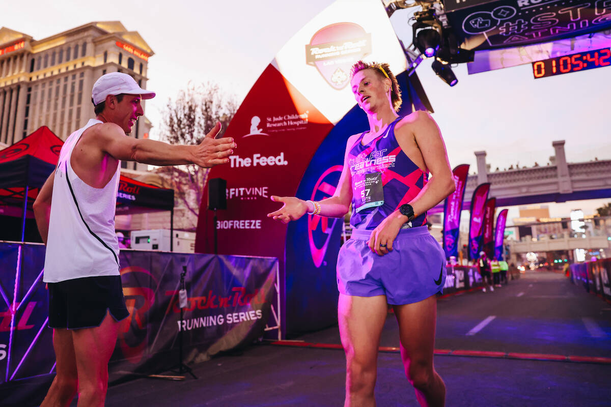 Andy Wacker, left, high fives another runner as he finishes his run during the Rock ’n&# ...