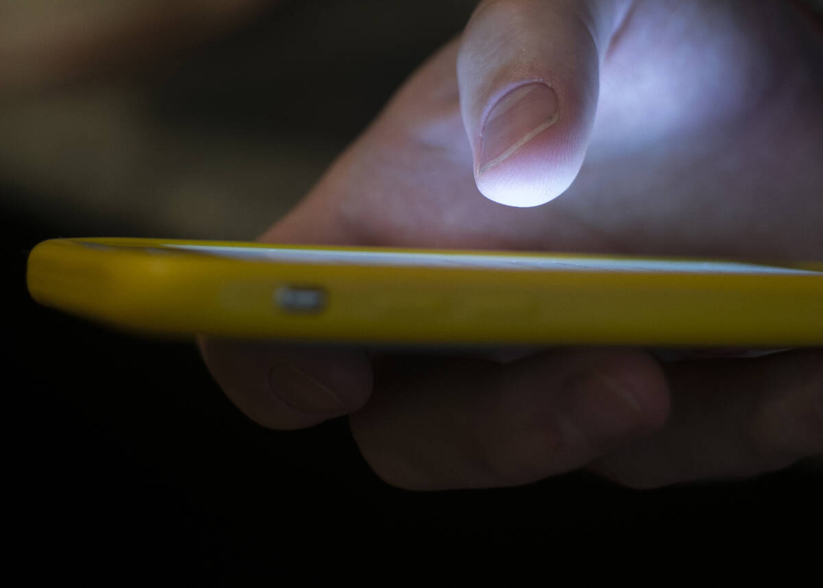 A man uses a cell phone in New Orleans on Aug. 11, 2019. (AP Photo/Jenny Kane, File)