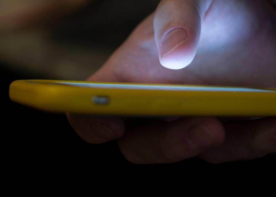 A man uses a cell phone in New Orleans on Aug. 11, 2019. (AP Photo/Jenny Kane, File)