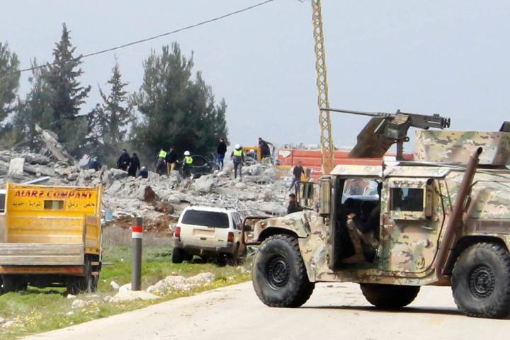 A Lebanese army vehicle block a road leading to a destroyed warehouse, background, which was at ...