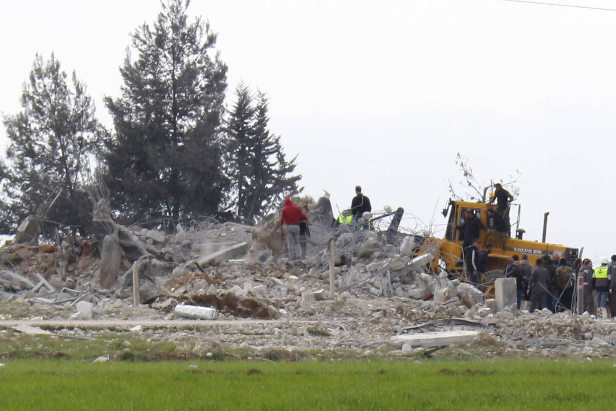 Civil defence workers gather near a destroyed warehouse which was attacked by Israeli airstrike ...