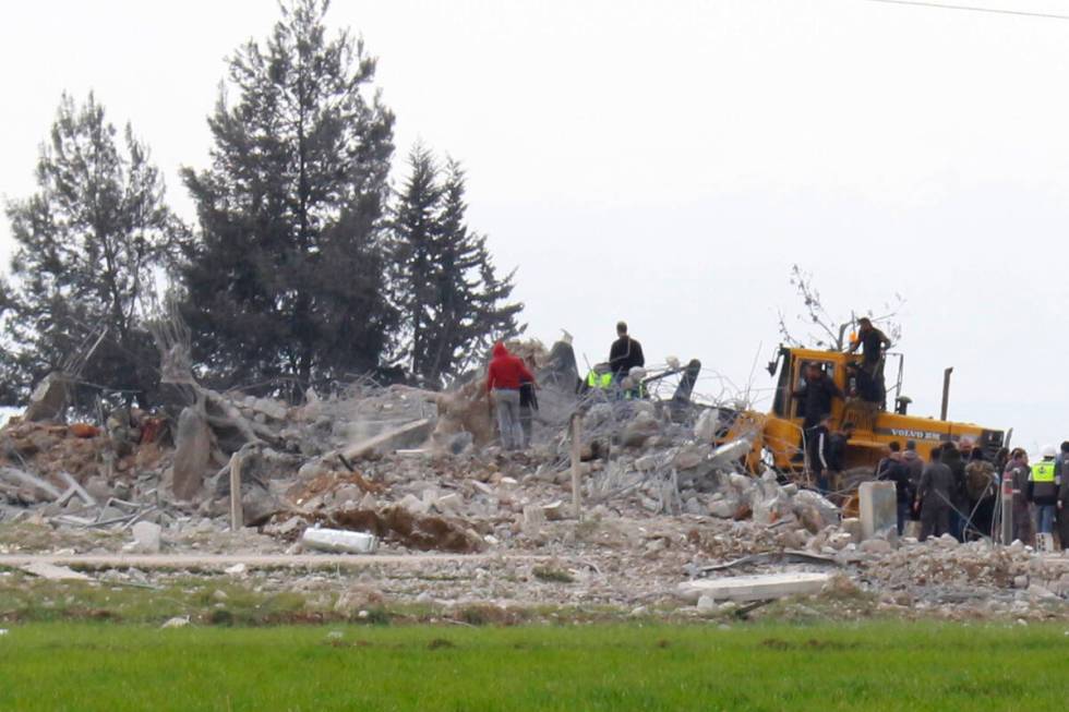 Civil defence workers gather near a destroyed warehouse which was attacked by Israeli airstrike ...