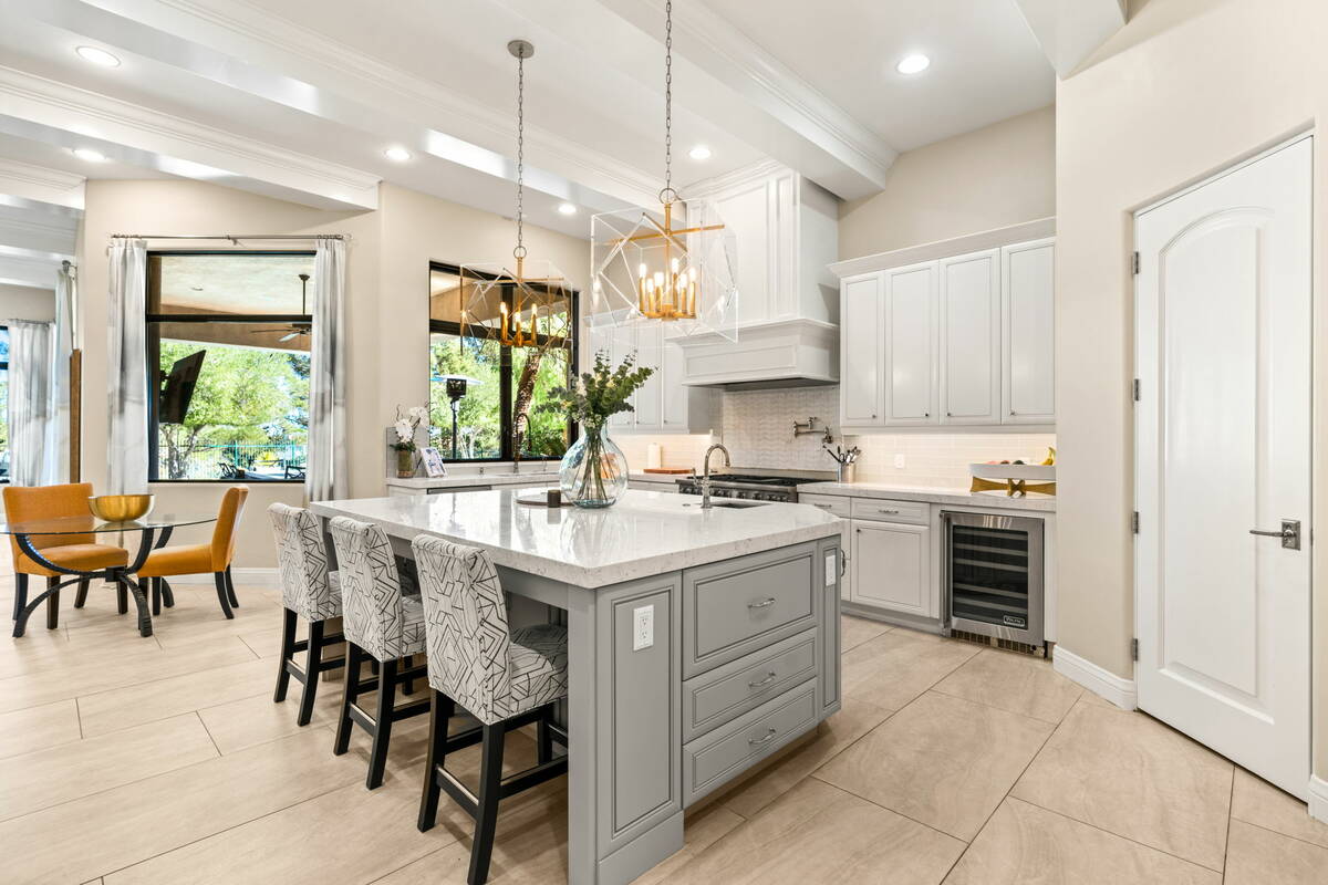 The John Sullivan Group The chef’s kitchen showcases custom white cabinetry and built-in ligh ...