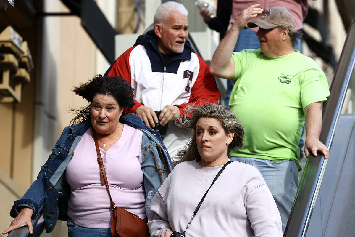 Visitors to the Las Vegas Strip walk on Las Vegas Boulevard despite a high wind warning on Satu ...