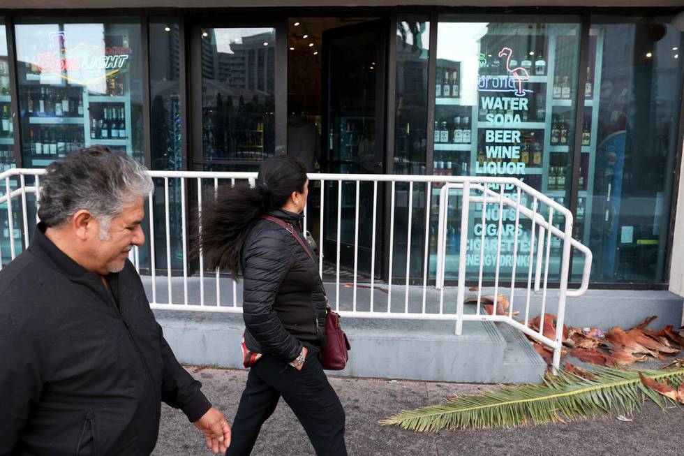 Visitors to the Las Vegas Strip walk on Las Vegas Boulevard despite a high wind warning on Satu ...