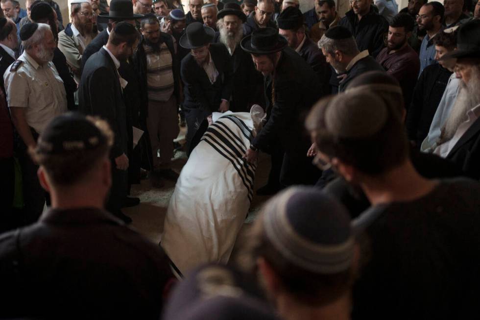 The body of Yitzhak Zeiger is placed in his grave during his funeral at a cemetery in Jerusalem ...