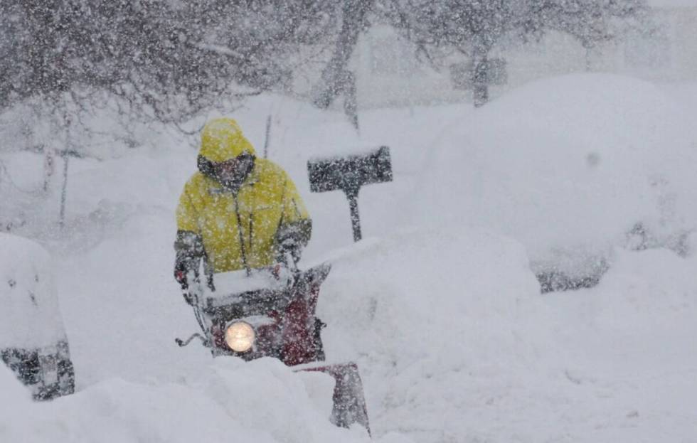 A person uses a blower to clear snow during a storm, Sunday, March 3, 2024, in Truckee, Calif. ...