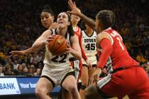 Iowa guard Caitlin Clark (22) drives to the basket between Ohio State guard/forward Taylor Thie ...
