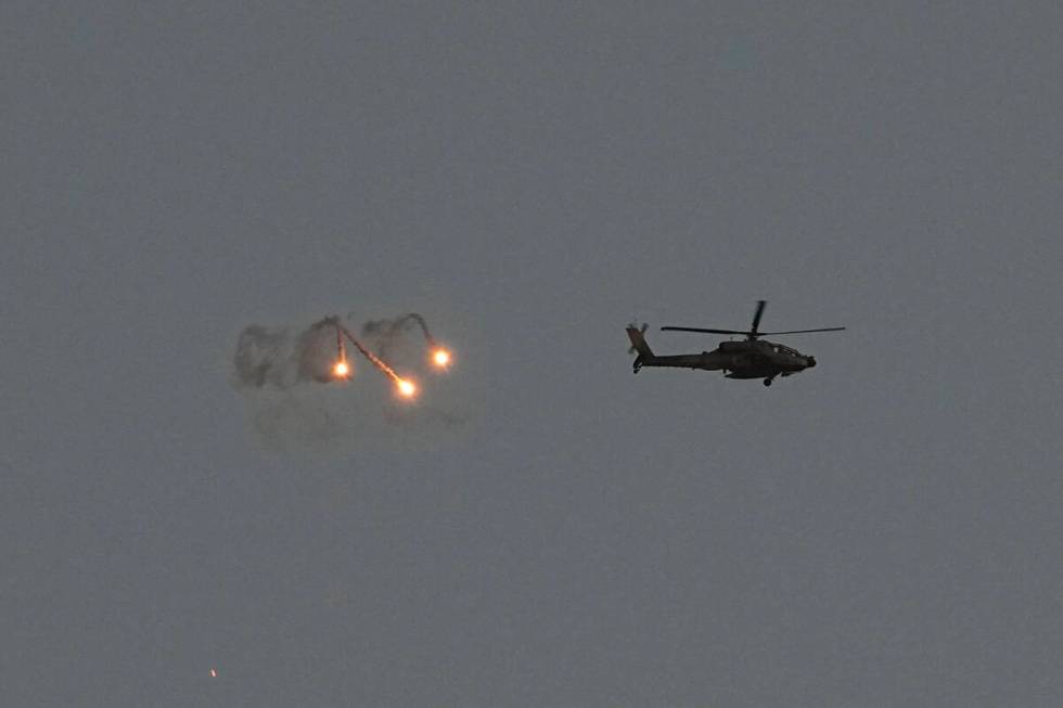 An Israeli Apache helicopter fires flares over the Gaza Strip as seen from southern Israel, Mon ...