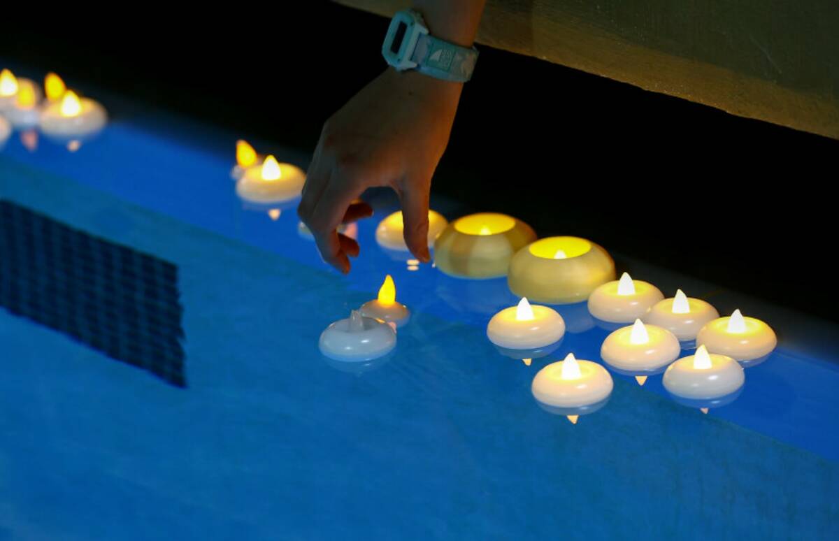 Loved ones of star swimmer Charlie Clark, 19, place candles in the water during a vigil at Hend ...