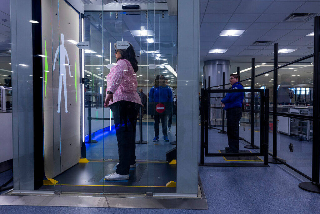 A Transportation Security Administration employee is body scanned as she demonstrates a self-se ...