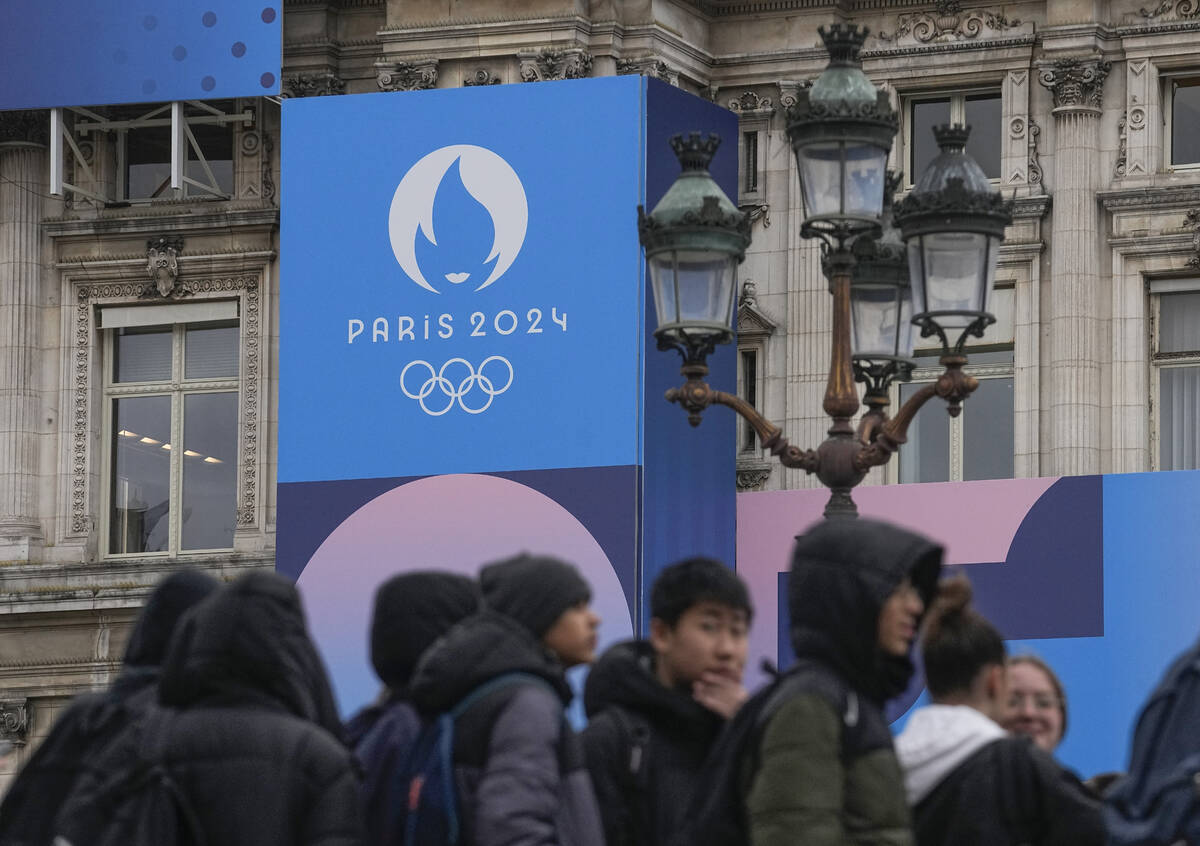 Youth gather at Paris City Hall where a Paris 2024 Olympic sign is displayed in Paris, Tuesday, ...