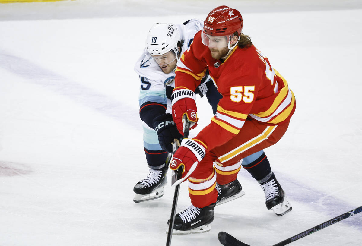 Seattle Kraken forward Jared McCann (19) checks Calgary Flames defenseman Noah Hanifin (55) dur ...