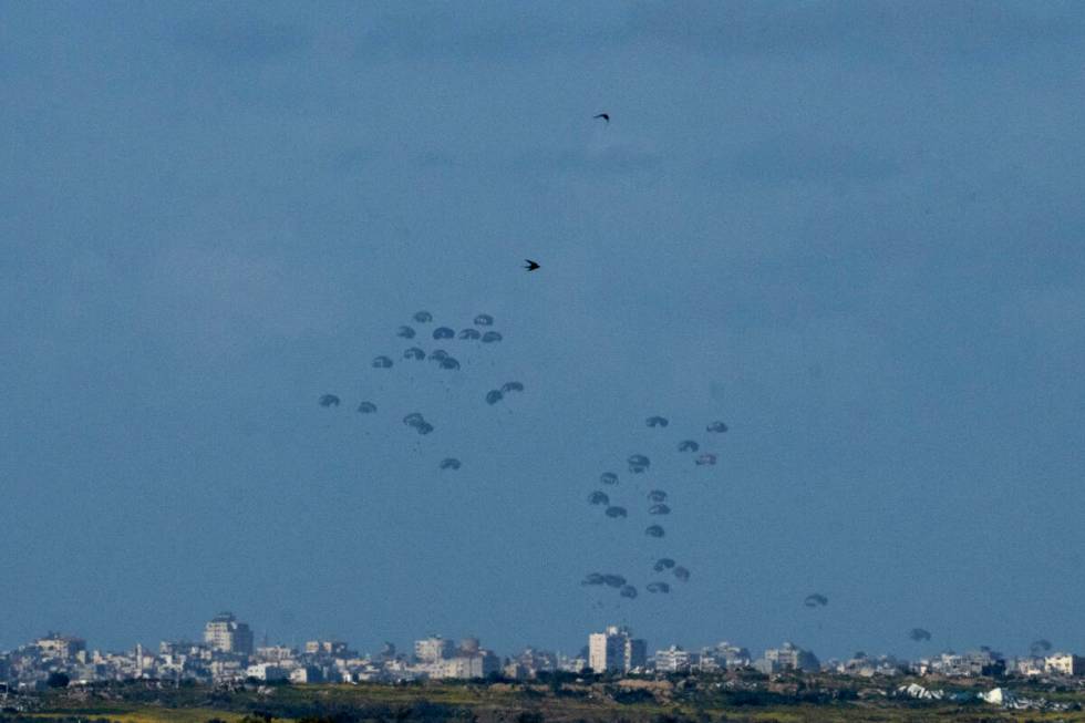 Parachutes drop supplies into the northern Gaza Strip, as seen from southern Israel, Thursday, ...